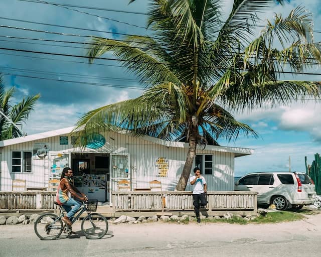 Man riding a bicycle outside a business on a beach in Jamaica