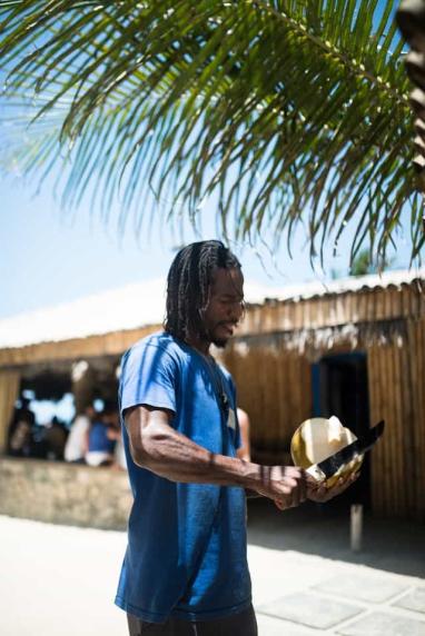Guy cutting a coconut on a beach