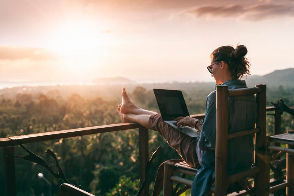 A Woman Working On Her Laptop During Sunset