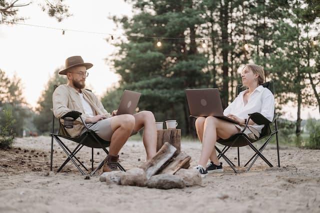Man and woman using their laptops on a camping site 