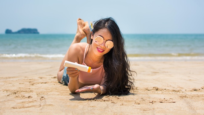 Woman applying sunscreen on a beach