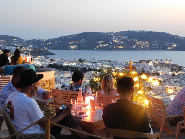 Group of people sitting with drinks overlooking the water on Mykonos, a Greek Island